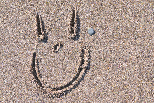 Cara sonriente dibujada sobre la arena de la playa