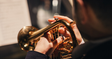 Cinematic Closeup of the Hands of a Male Trumpet Player Reading a Music Sheet and Playing his Instrument. Professional Musician Rehearsing Before the Start of a Big Jazz Show - obrazy, fototapety, plakaty