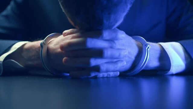 Arrested criminal businessman in handcuffs in the interrogation room. Arrest of the offender. Detention and interrogation of the accused man.