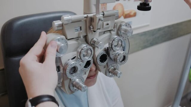 woman looking through optical Phoropter during eye exam, The expert is testing the vision test with diagnostic ophthalmology equipment, selective focus