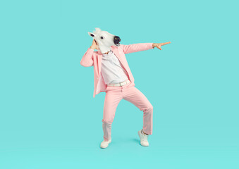 Full length photo of funny man wearing bright pink suit in animal head horse mask dancing on studio blue background. Guy having fun. Entertainment, party, humor and advertisement concept.