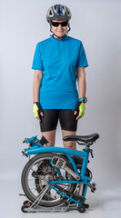 Fototapeta premium Gennevilliers, France - 04 10 2023: Studio shot detail of a woman dressed in a blue polo shirt, black shorts and a bicycle helmet, poses next to her blue folding bicycle.