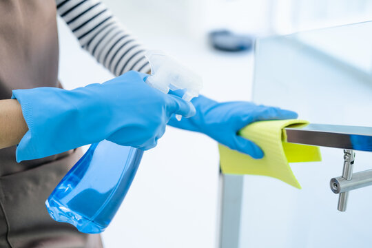 Maid cleaning stairway rail by using alcohol and liquid cleaning solution. alway cleaning equipments in daily life. Sanitation and healthcare.