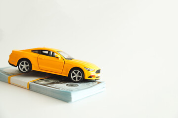 Toy Car Hanging on a Stack of Money on a White Background. Concept Car Expenses, loan payment