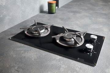 Contemporary black tempered glass gas stove hob with Two burners with auto ignition knob cast iron pan supports and flame safety valve built in compact high pressure laminate HPL countertop.
