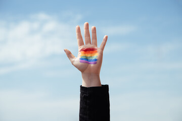 Girl with the palm of her hand painted with the rainbow flag.