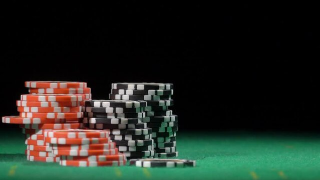 Throws black chip, slow motion. Red and black chip stacks on green gaming table.