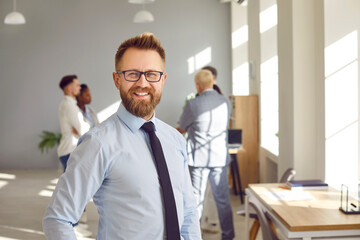 Portrait of happy smiling confident bearded business man leader in glasses wearing blue shirt and...