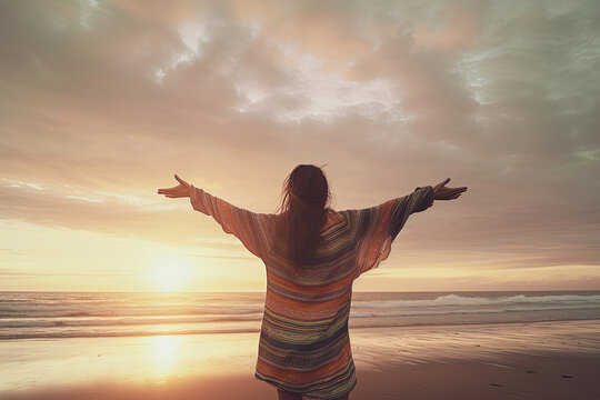 A happy woman greeting the sun with raised arms at the beach