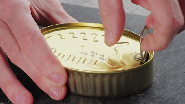 Opening canned octopus squid fish can, man open the canned seafood on the table. Close up on professional kitchen.