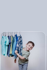 Fototapeta na wymiar Cheerful boy peeking through clothes hanger - Joyful and Playful Childhood Moment