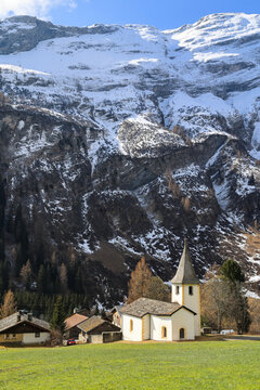 The reformed church in the idyllic Alps village of Medels im Rheinwald against snow mountain at the background, Grisons, Switzerland