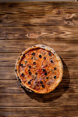Pizza with tuna, olives, onions, mozzarella cheese and tomato sauce on wood background. Top view, copy space