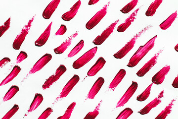 Smears of red cosmetic lipstick on a light background.