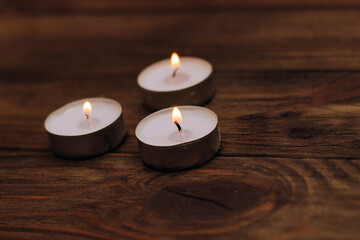 Fototapeta na wymiar Three paraffin floating candles on a wooden table.