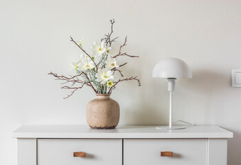 Minimalism style interior decor - flower arrangement in a ceramic vase and a white metal table lamp...