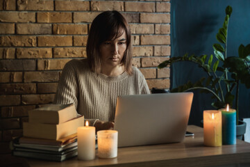 Young woman using laptop to work at home during electricity outage. Remote work at home concept....
