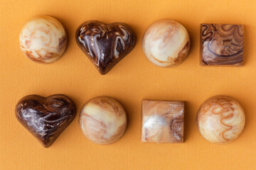 Set of homemade brown chocolate bonbons. Assortment of hand painted candies with marble coating. Mockup with a copy space. Macro shot of  chocolatier products on yellow background. Top view