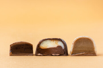 Set of homemade brown chocolate bonbons slice. Assortment of hand painted candies. Candy cut in a half. Mockup with a copy space. Macro shot of  chocolatier products on beige background