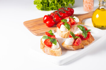 Tomato, basil and cheese fresh made caprese bruschetta. Italian tapas, antipasti with vegetables, herbs and oil on grilled ciabatta and baguette bread. Sandwich.