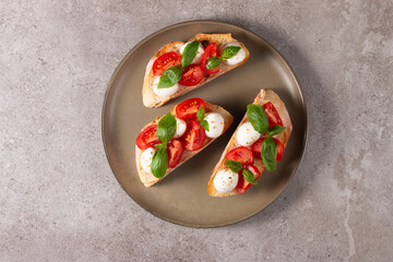 Tomato, basil and cheese fresh made caprese bruschetta. Italian tapas, antipasti with vegetables, herbs and oil on grilled ciabatta and baguette bread. Sandwich.