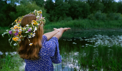 girl in flower wreath outdoor, abstract natural green background. rear view. Floral crown, symbol...