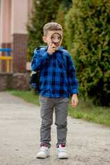 Fototapeta premium Schoolboy looking through a magnifying glass, with a surprised expression, squinting his eyes