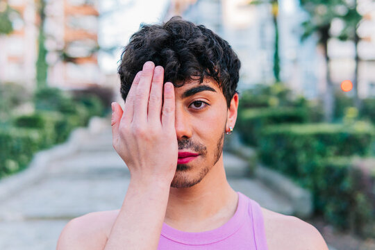 Man from the lgbt collective with makeup, covering his face with his hand in protest against homophobia