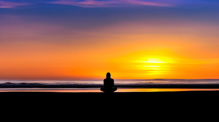 Silhouette of a person practicing mindfulness overlooking the ocean at sunset with their back to the camera