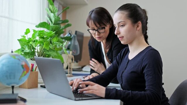 Teenage girl studying, female teacher with textbook helps tells teaches