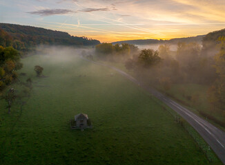 Aerial drone Sunrise view Above autumn colored forest and Valleys in Luxembourg, covered in morning fog