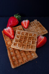 Belgian waffles with strawberries on a black background.