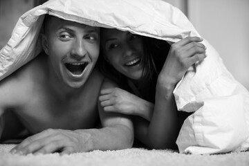 Young happy couple lying together in bed