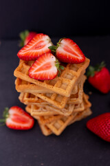 Belgian waffles with strawberries on a black background.
