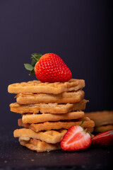 Belgian waffles with strawberries on a black background.