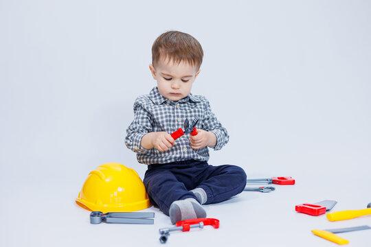 A cute boy in a shirt in the image of a builder, on a white background. Childhood, learning, work, games, career, imitation. Little daddy's helper.