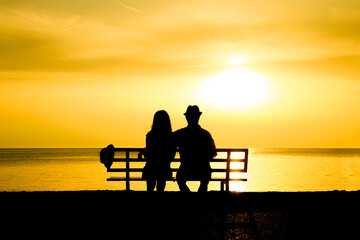 Fototapeta na wymiar A happy couple on a bench by the sea on nature in travel silhouette