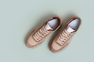 Beige women's leather sneakers top view on a green background. Spring or autumn shoes