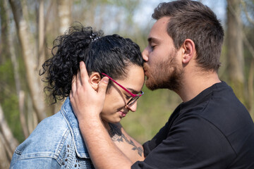 baiser sur le front d'un jeune homme à une jeune femme en forêt