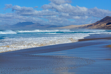View on difficult to access golden sandy Cofete beach hidden behind mountain range on Fuerteventura, Canary islands, Spain