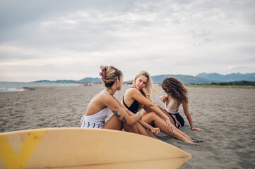 Obraz premium Three beautiful woman friends sitting on a beach and having fun