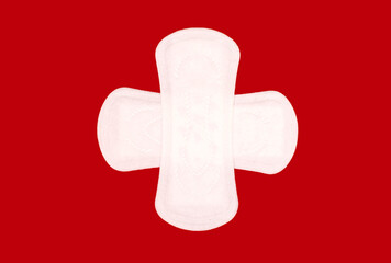 Two feminine hygiene menstrual pads arranged in the shape of a cross on a red background. Feminine hygiene product in the form of a sanitary napkin. Clean menstrual pads