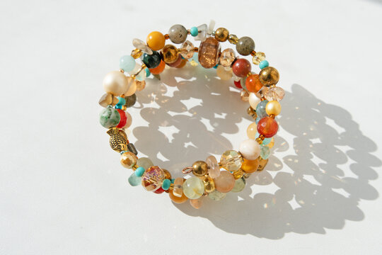 many-sided fashionable author  bracelet  with various natural semipreciouse stones and christals around white backgroynd with shadows