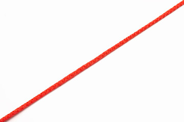 Red rope located diagonally on a white isolated background. A red line in the form of a rope divides the white background in half. Free space for text. Red thread on a white background