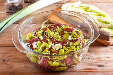 Raw juicy beef fillet medallion topped with leek on table