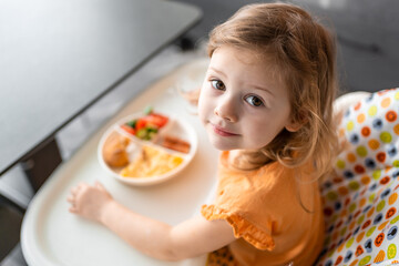 Little girl have a balanced breakfast in home kitchen in the morning