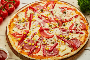 Freshly baked tasty pepperoni pizza with salami, mozzarella cheese, corn and pepper served on wooden background with tomatoes, sauce and herbs. Food delivery concept. Restaurant menu