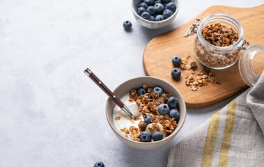 The concept of a healthy breakfast of yogurt, granola and fresh blueberry on a light background. Homemade diet and protein food.
