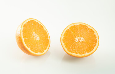 Two halves of an orange with reflection on a white mirror background