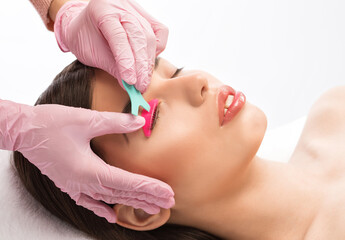 Make-up artist makes the procedure of lamination and dyeing of eyelashes to a beautiful woman in a beauty salon. Eyelash extensions. Eyelashes close-up